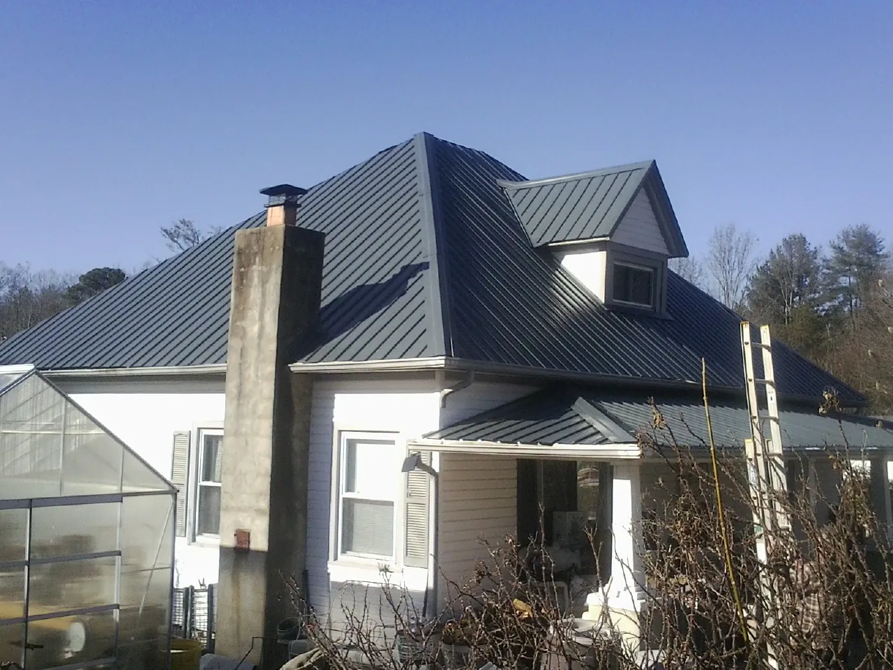 Dark blue standing seam metal roof on a white farmhouse with dormer — Slate & Tile Roof Repair by Roofing Brothers in Morven