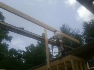 Carpenter setting a ridge beam over a new addition frame — Ice Dam Removal by Roofing Brothers in Morven