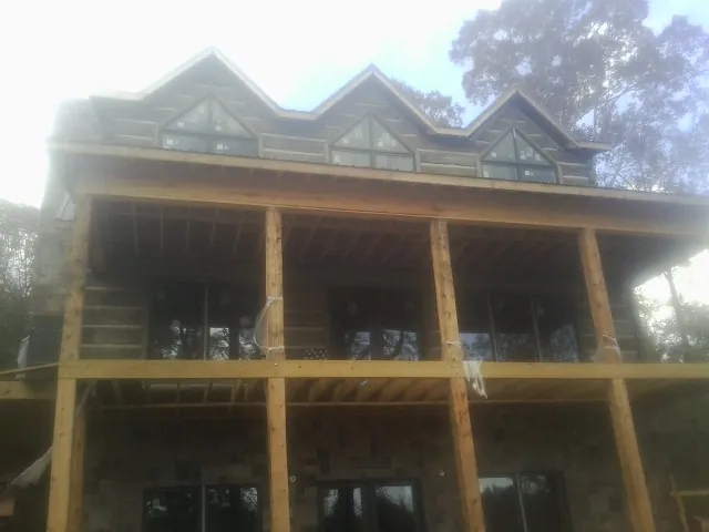 Dormers and porch framing on a large log home under construction — Roof Coating work by our crew in Morven