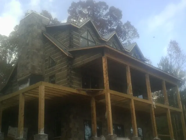 Stone chimney and dormers on a large log home with a timber porch in Morven