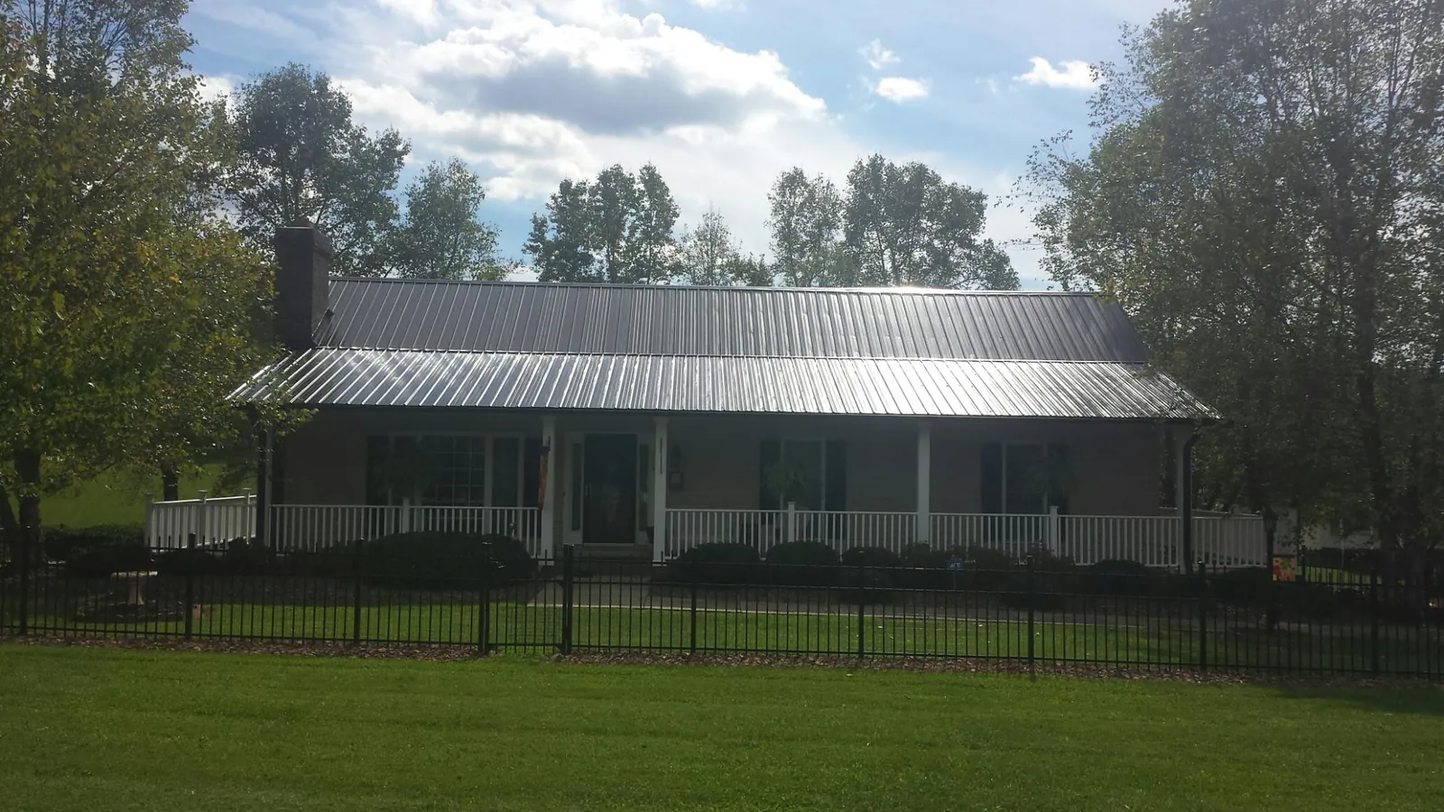 Gray metal roof on a brick ranch with a full width front porch — Gutter Guard Installation work by our crew in Morven