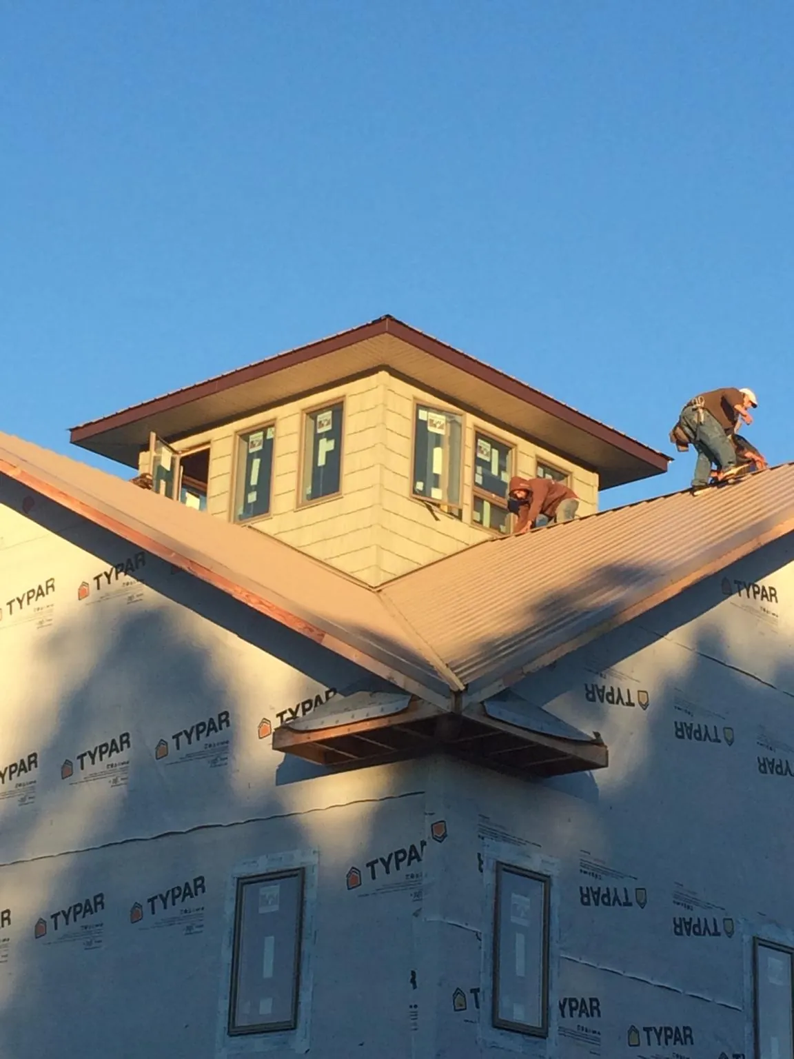 Roofers working around a rooftop cupola on a new metal roof at sunset — Roof Waterproofing in Morven by Roofing Brothers